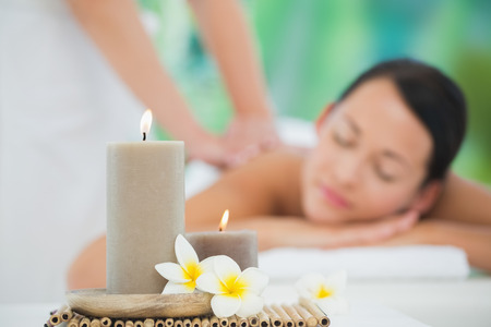 Beautiful brunette enjoying a back massage smiling at camera at a luxury spaの写真素材