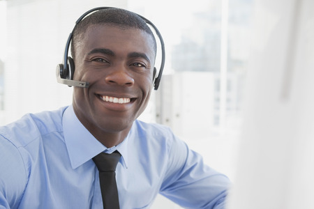 Happy businessman working at his desk wearing headset in his office