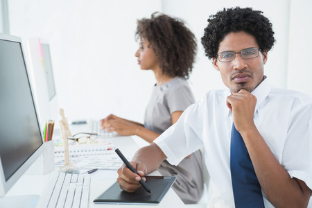 Young designer looking at camera at his desk in creative officeの写真素材