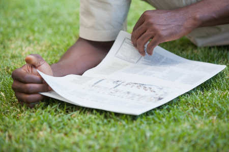 Man relaxing in his garden reading newspaper on a sunny day