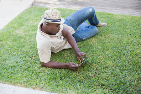 Smiling man relaxing in his garden using tablet pc on a sunny dayの写真素材