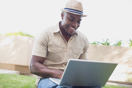 Handsome man relaxing in his garden using laptop on a sunny dayの写真素材