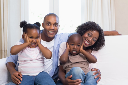 Happy family posing on the couch together at home in the living roomの写真素材