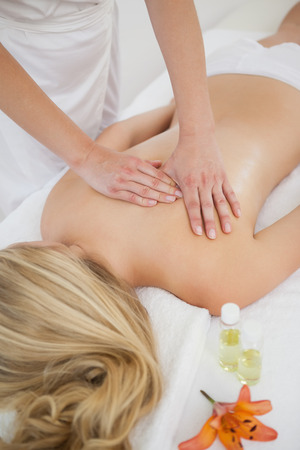 Blonde enjoying a back massage at the health spaの写真素材