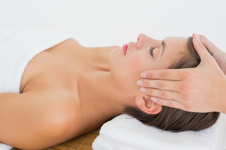 Side view of an attractive young woman receiving head massage at spa centerの写真素材