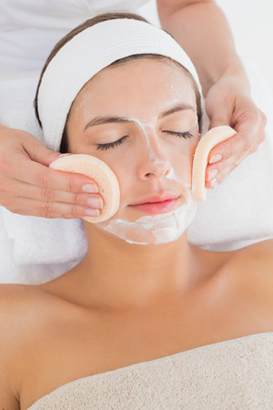 Hand cleaning woman's face with cotton swabs at spa centerの写真素材