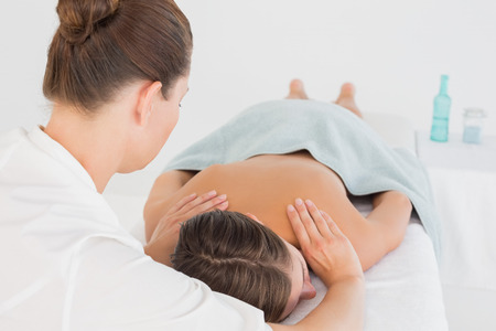 Close-up of an attractive young woman receiving shoulder massage at spa centerの写真素材