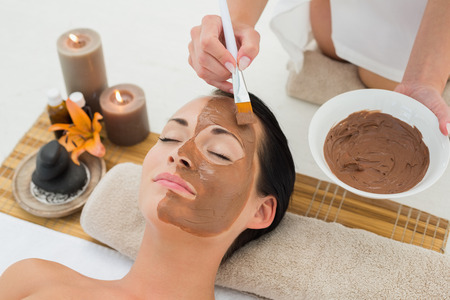 Peaceful brunette getting a mud facial applied in the health spaの写真素材