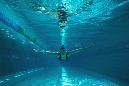 Athletic swimmer training on her own in the swimming pool at the leisure centreの写真素材