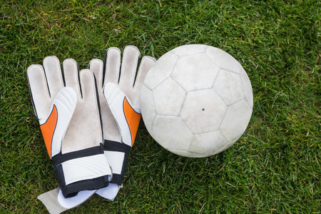 Goalkeeping gloves and football on pitch on a clear dayの写真素材