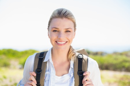 Attractive hiking blonde smiling at camera on a sunny dayの写真素材