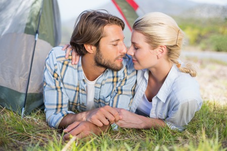 Attractive couple lying in their tent about to kiss on a sunny dayの写真素材