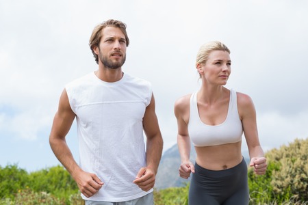 Attractive couple jogging on mountain trail on a sunny dayの写真素材