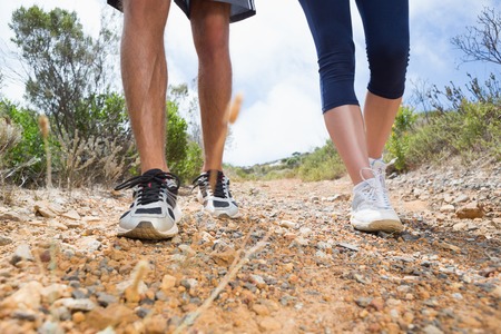 Fit couple walking down mountain trail on a sunny dayの写真素材