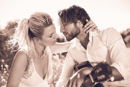 Handsome man serenading his girlfriend with guitar in sepia tones