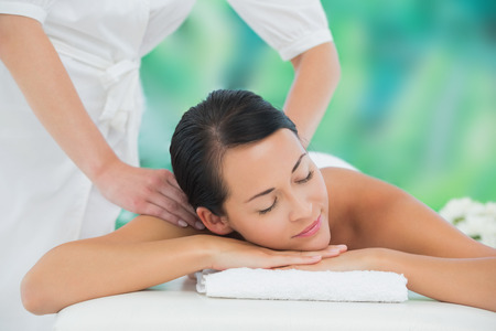 Beautiful brunette enjoying a back massage at a luxury spaの写真素材