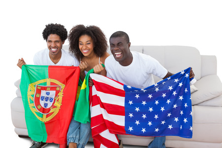 Cheering football fans holding flags on the sofa on white backgroundの写真素材