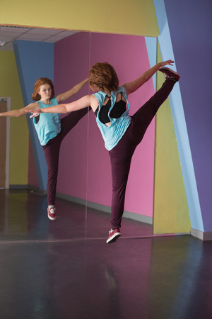 Pretty break dancer jumping up and looking in mirror in the dance studioの写真素材