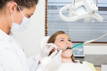 Pediatric dentist examining little girls teeth in the dentists chair at the dental clinicの写真素材