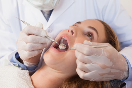 Dentist examining a patients teeth in the dentists chair at the dental clinicの写真素材