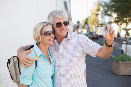 Happy tourist couple taking a selfie in the city on a sunny dayの写真素材