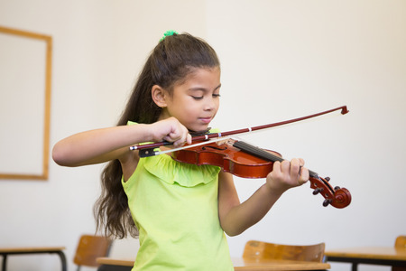 Cute pupil playing violin in classroom at the elementary schoolの写真素材