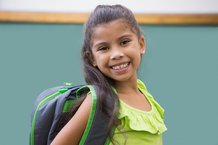 Cute pupil smiling at camera in classroom at the elementary school