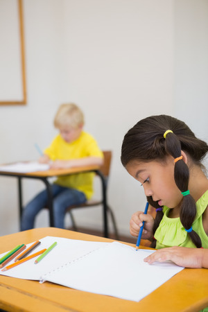Cute pupils colouring at desks in classroom at the elementary schoolの写真素材