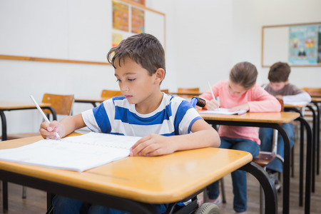 Disabled pupil writing at desk in classroom at the elementary schoolの写真素材