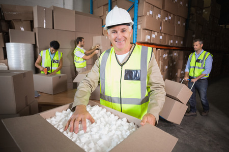 Warehouse workers in yellow vests preparing a shipment in a large warehouse