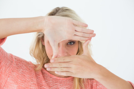 Portrait of young woman making frame with her hands over white backgroundの写真素材