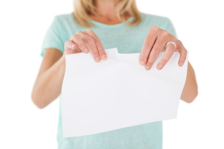 Close up mid section of woman holding torn sheet of paper over white backgroundの写真素材