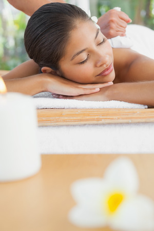 Beautiful brunette enjoying a herbal compress massage at the health spaの写真素材
