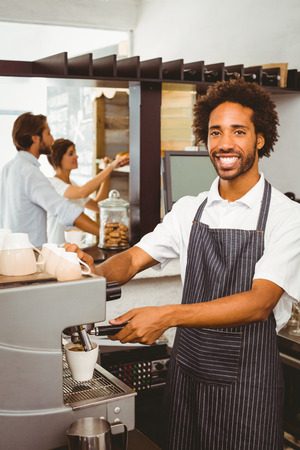 Handsome barista making a cup of coffee at the coffee shopの写真素材