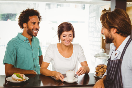 Barista talking with two customers at the coffee shopの写真素材