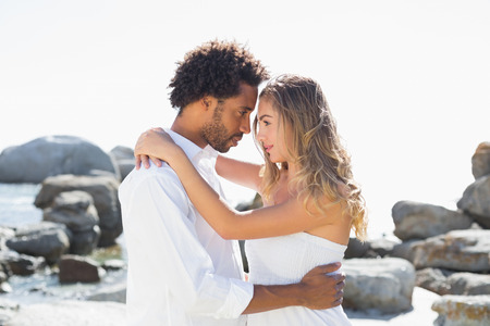 Gorgeous couple embracing at the coast on a sunny dayの写真素材