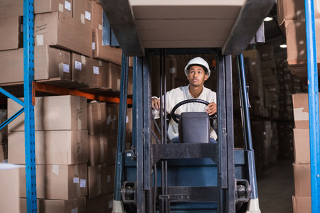 Forklift driver operating the machine in a large warehouseの写真素材
