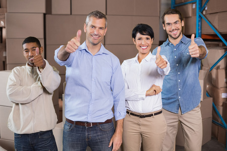 Warehouse workers smiling at camera in a large warehouseの写真素材