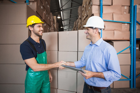 Warehouse worker loading up a pallet with manager in a large warehouse