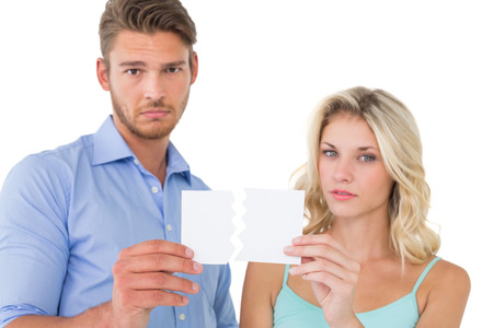 Upset couple holding torn piece of paper on white backgroundの写真素材