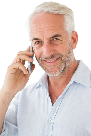 Smiling mature man using mobile phone over white backgroundの写真素材