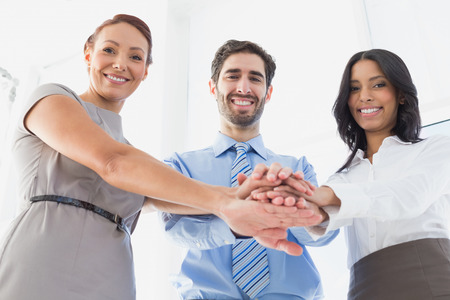 Workers with stacked hands smiling together