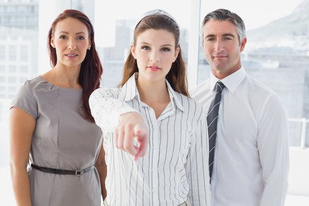 Smiling businesswoman pointing at camera in the officeの写真素材