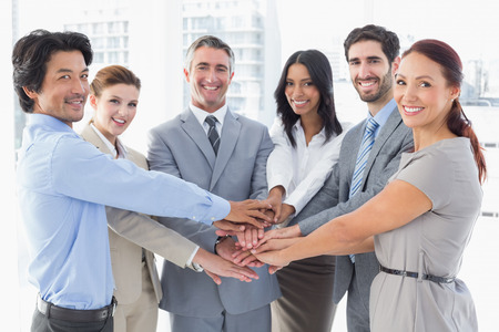 Business team stacking their hands together while smiling