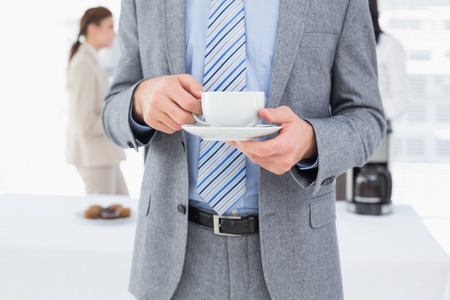 Smiling businessman with a drink at workの写真素材
