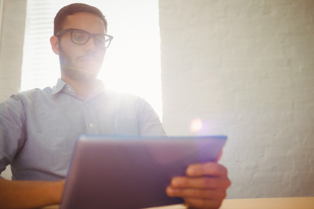 Casual businessman using his tablet at his desk in his officeの写真素材