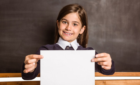 Cute pupil showing white page in classroomの写真素材