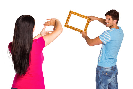 Young couple hanging a frame on white backgroundの写真素材