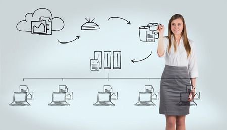 Smiling businesswoman writing with whiteboard marker against grey vignetteの写真素材