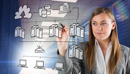 Smiling businesswoman writing with pen against server room with towersの写真素材